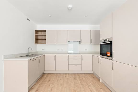 A kitchen with white cabinets and a wooden floor.at The Quarters Apartments, Dock Road, ME4 4UB