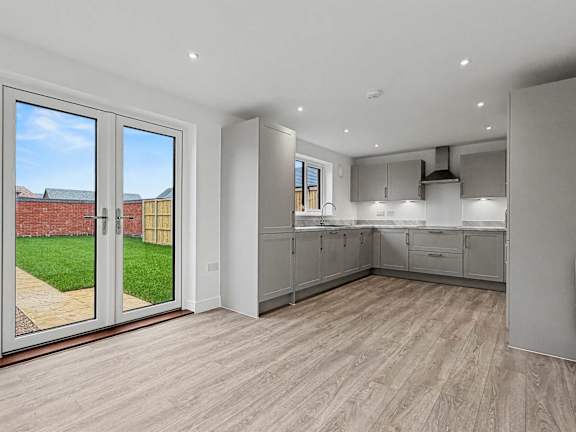 A kitchen with a view of a backyard through the sliding glass doors.