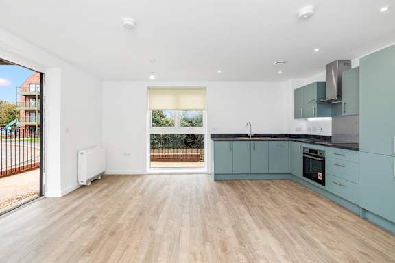 A spacious kitchen with teal cabinets and a white fridge.