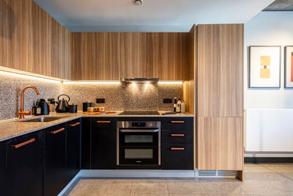 A modern kitchen with black cabinets and wooden accents.