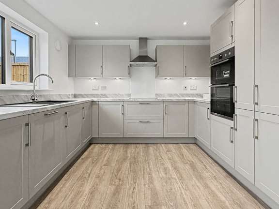 A modern kitchen with wooden floors and white cabinetry.
