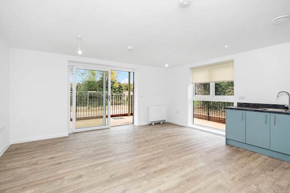 A spacious room with wooden flooring and white walls.