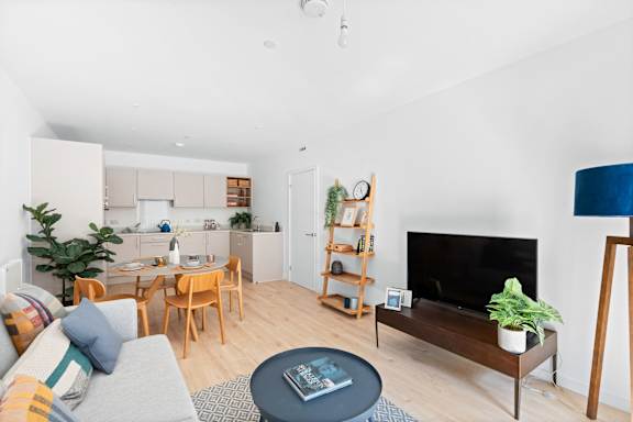 A living room with a grey sofa, a coffee table, a television, and a fireplace.at The Quarters Apartments, Dock Road