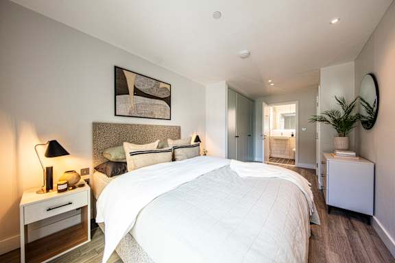 A bedroom with a large bed and a painting on the wall.