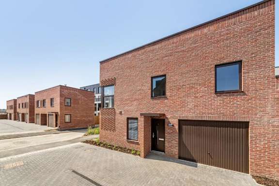 A red brick building with a black garage door at Origins Apartments, Cambridge