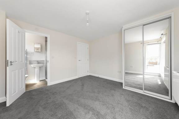 A large, empty room with a carpeted floor and white walls at Origins Apartments, Cambridge, CB3 0UX