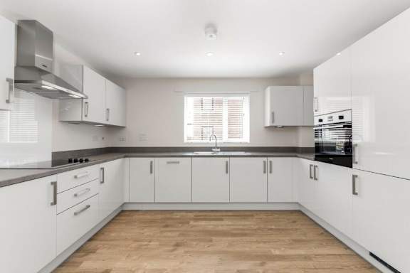 A kitchen with white cabinets and a wooden floor at Origins Apartments, Cambridge, CB3 0UX