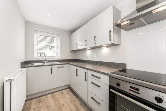 A modern kitchen with white cabinets and stainless steel appliances at Origins Apartments, Cambridge