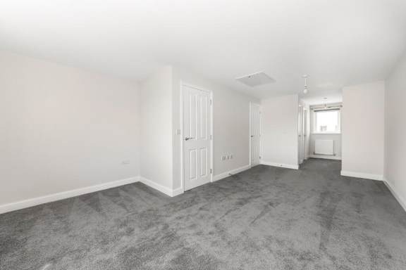 A spacious room with grey carpeting and white walls at Origins Apartments, Cambridge