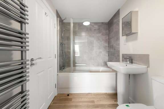 A white bathroom with a tub and a toilet at Origins Apartments, Cambridge, CB3 0UX