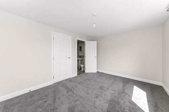 A room with a grey carpet and two white doors at Origins Apartments, Cambridge