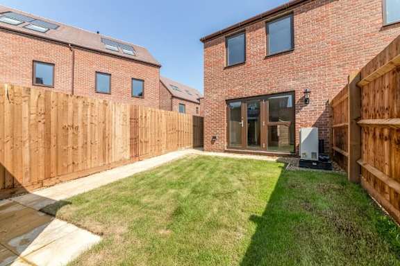 A backyard with a wooden fence and a brick house at Origins Apartments, Cambridge