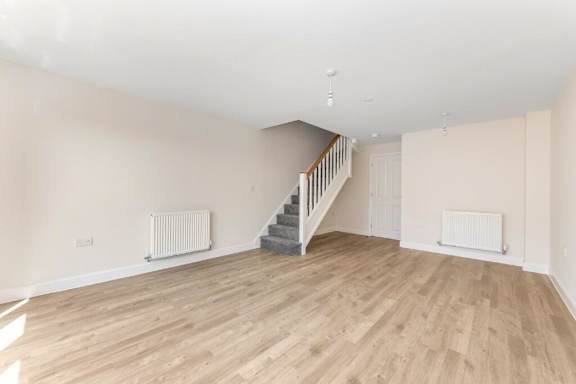 A spacious room with wooden flooring and a staircase at Origins Apartments, Cambridge, CB3 0UX