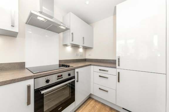 A modern kitchen with white cabinets and a stainless steel oven at Origins Apartments, Cambridge