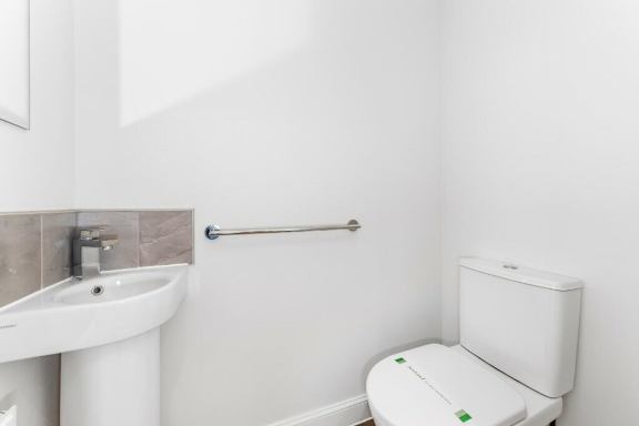 A white toilet with a white sink and a towel rack in a bathroom at Origins Apartments, Cambridge