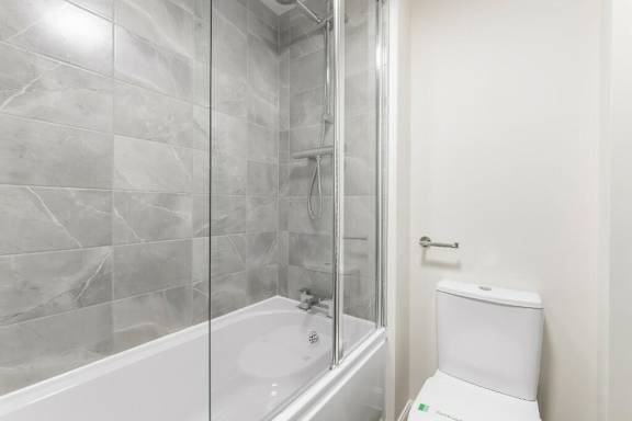 A white toilet sit next to a bathtub in a bathroom at Origins Apartments, Cambridge, CB3 0UX