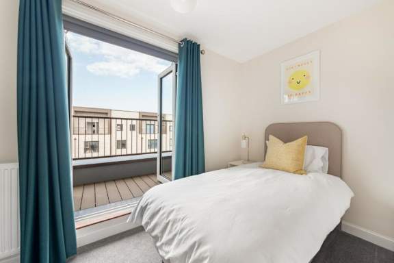 A bedroom with a large bed and a view of a balcony at Origins Apartments, Cambridge, CB3 0UX