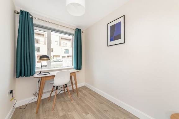 A room with a desk and chair in front of a window with a view of a building outside at Origins Apartments, Cambridge, CB3 0UX