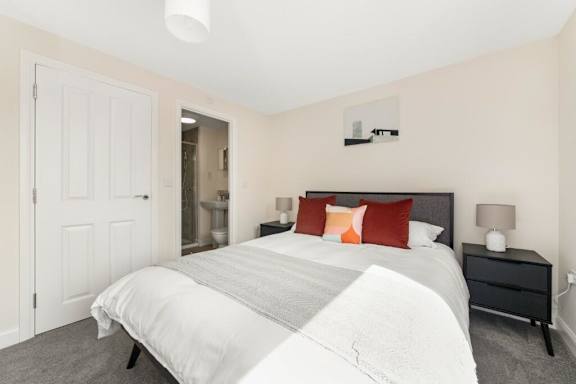 A bedroom with a white bed and a black nightstand at Origins Apartments, Cambridge