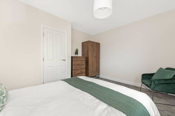 A bedroom with a bed, a chair, and a cabinet at Origins Apartments, Cambridge, CB3 0UX