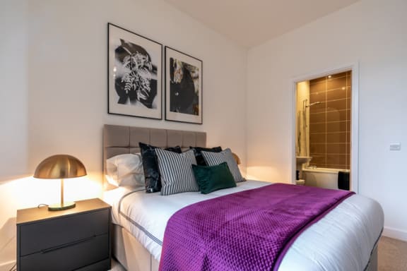 a bedroom with a large bed and a purple blanket at The Keel Apartments, Liverpool