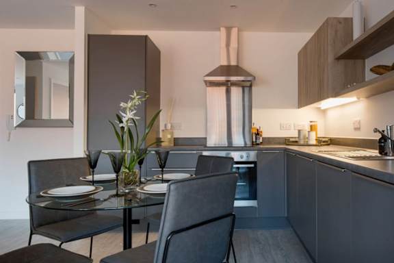 a kitchen and dining room with a table and chairs a kitchen and dining room with a table and chairs at Vox Apartments, Manchester