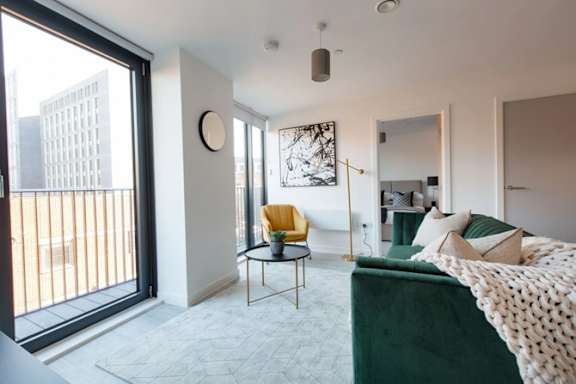 a living room with a green couch and a large window a living room with a green couch and a large window at Vox Apartments, Manchester, M15 4YD