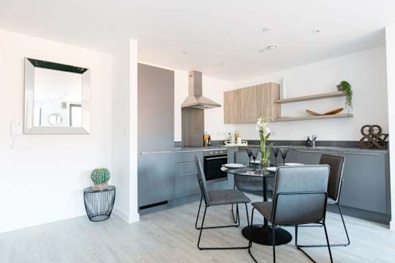 a kitchen and dining area with a table and chairs a kitchen and dining area with a table and chairs at Vox Apartments, Manchester