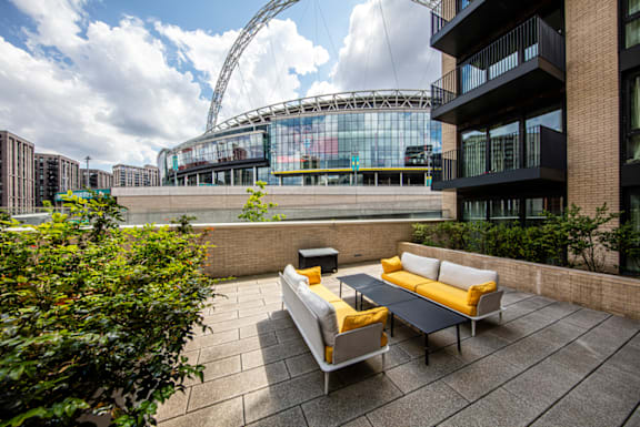 A patio with a couch and a table in front of a building.