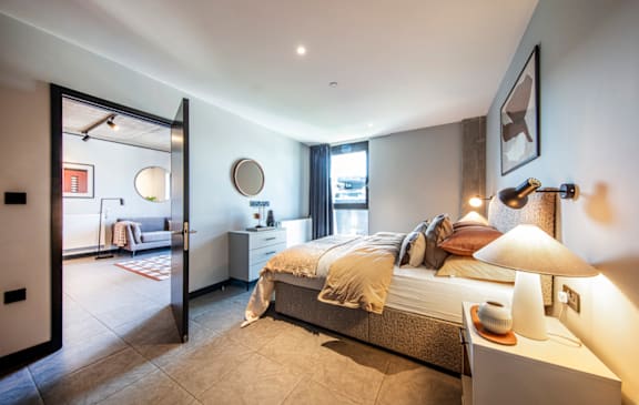 A bedroom with a bed, nightstand, and lamp.