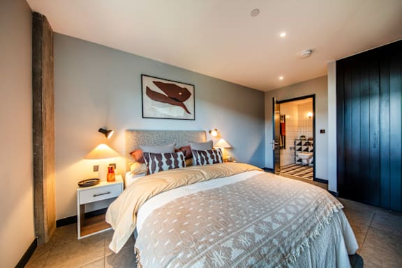 A bedroom with a large bed and a painting above it.