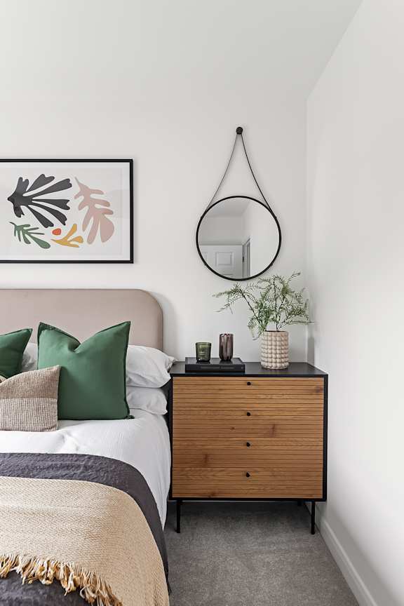 A bedroom with a bed, a dresser, and a mirror at The Woodlands Apartments, Milton Keynes