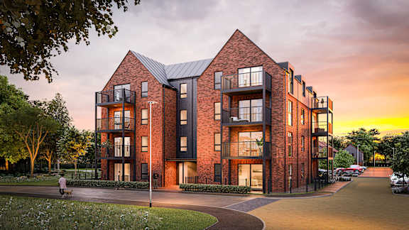 A red brick building with a black roof and a person walking in front at The Woodlands Apartments, Milton Keynes