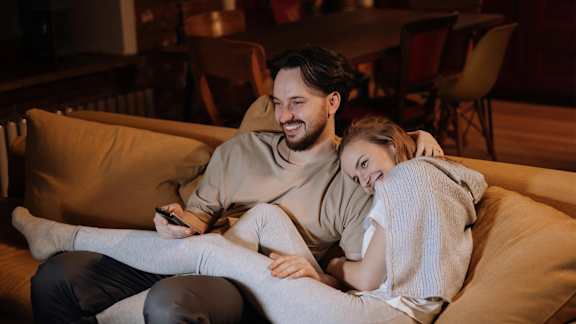 A man and a woman are sitting on a couch, the man is holding a phone.