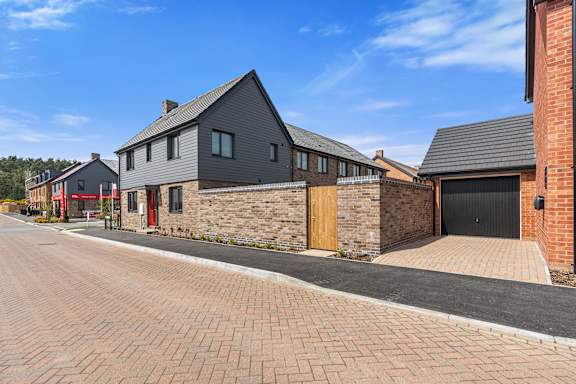 A modern house with a black roof and a red door.