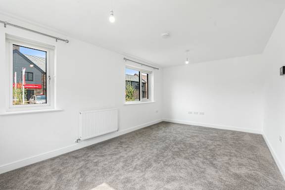 A spacious room with a grey carpet and white walls.