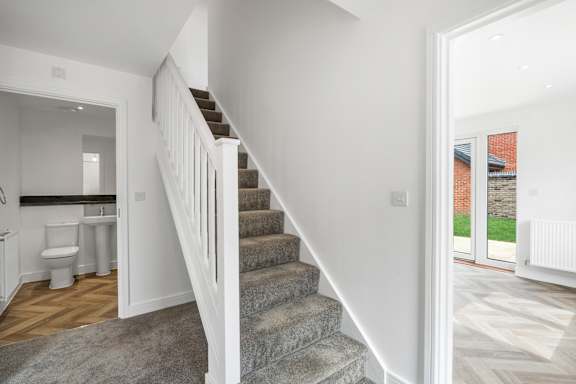 A white staircase leads to a bathroom and a kitchen area.