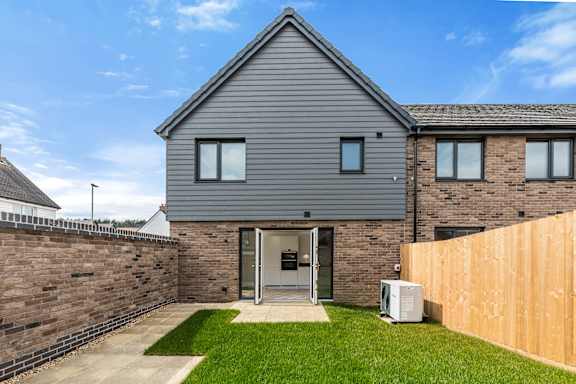 A modern house with a grey roof and a wooden fence.