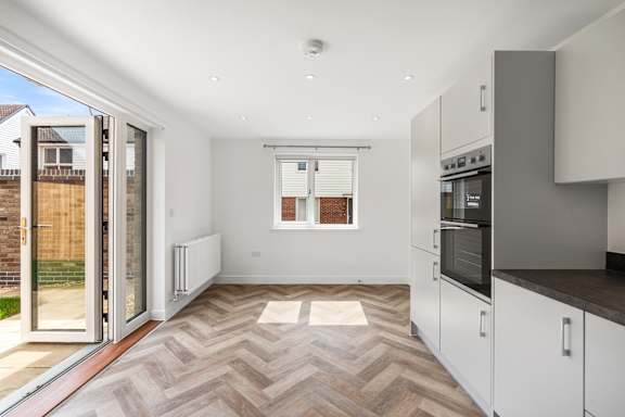 A modern kitchen with a wooden floor and white cabinets.