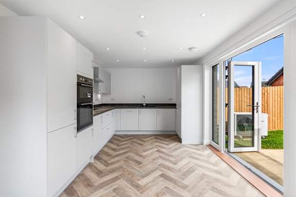 A modern kitchen with white cabinets and a wooden floor.