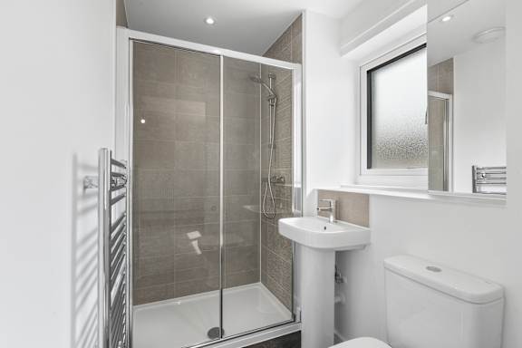 A white bathroom with a walk in shower and a toilet.