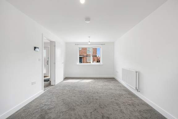 A spacious, empty room with a carpeted floor and white walls.