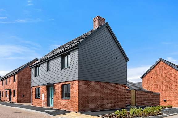 A modern house with a grey facade and a brick wall.