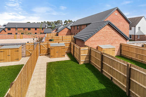 A backyard with a wooden fence and a green lawn.