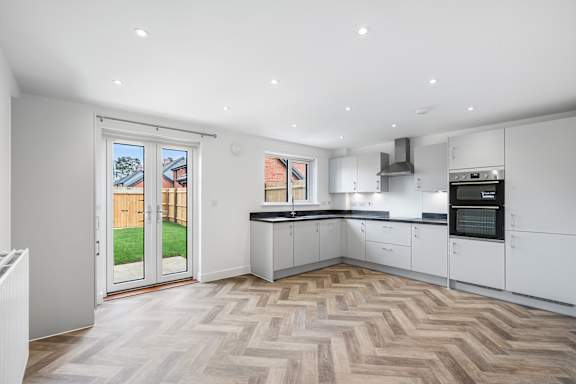 A modern kitchen with a white color scheme and a herringbone patterned floor.