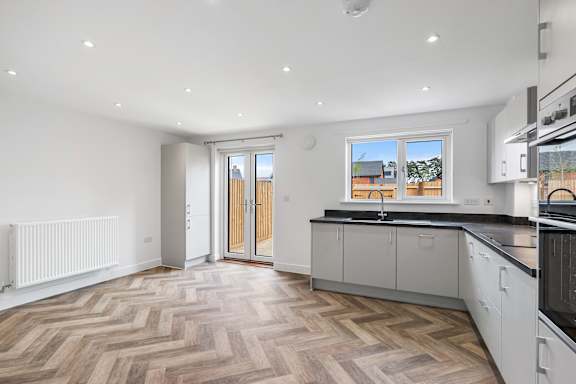 A kitchen with a wooden floor and white walls.
