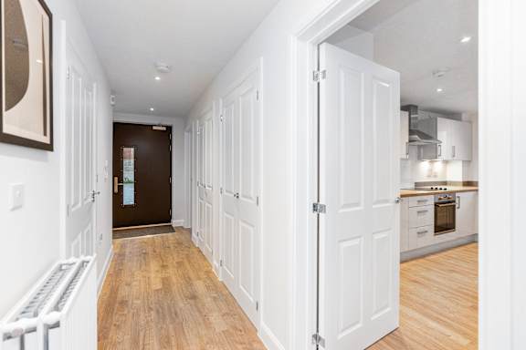 A hallway with white doors leading to a kitchen.