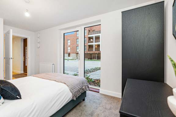 A bedroom with a large bed and a view of a courtyard outside.