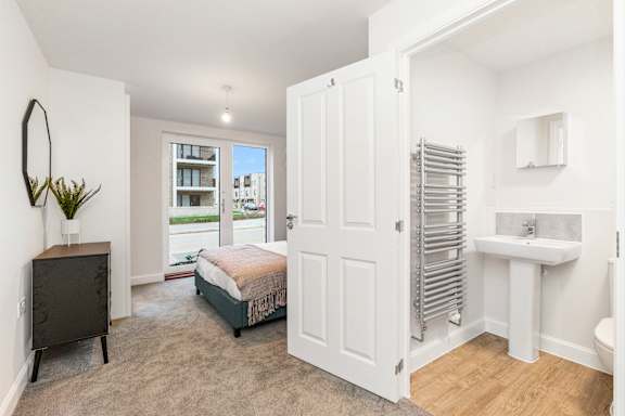 A white bathroom with a towel rack and a mirror.
