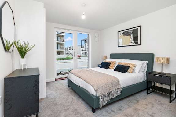 A bedroom with a large bed and a view of a street outside the window.